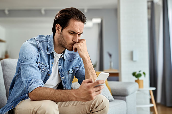 Man in denim shirt looking thoughtfully at his phone, reflecting on a relationship and passion for pastries at home. Man in denim shirt looking thoughtfully at his phone, reflecting on a relationship and passion for pastries at home.