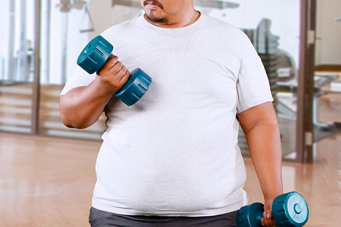 Man lifting dumbbells indoors, illustrating guy vents online about girlfriend wanting him to close her closet door. Man lifting dumbbells indoors, illustrating guy vents online about girlfriend wanting him to close her closet door.