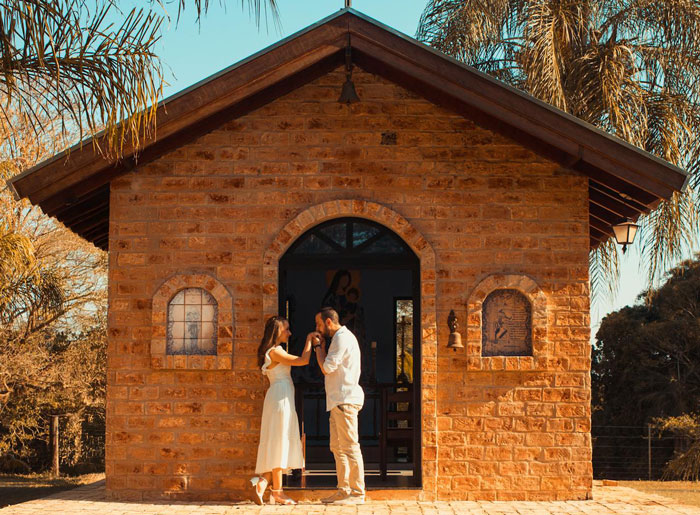 Couple standing outside a small brick chapel, symbolizing a small wedding and family relationship tension.