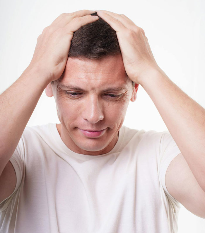 Man holding head in distress, symbolizing conflict in family relationships over small wedding plans.