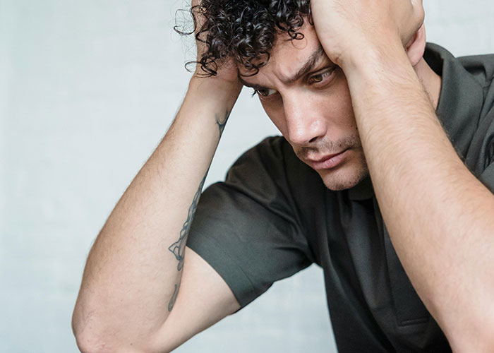 Man looking distressed and holding his head, representing phone dependence affecting family relationships. Man looking distressed and holding his head, representing phone dependence affecting family relationships.