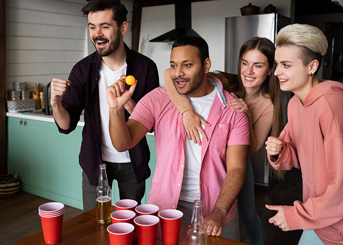Group of friends playing beer pong in kitchen, highlighting party scene related to boyfriend ditching newborn for over 18 hours. Group of friends playing beer pong in kitchen, highlighting party scene related to boyfriend ditching newborn for over 18 hours.