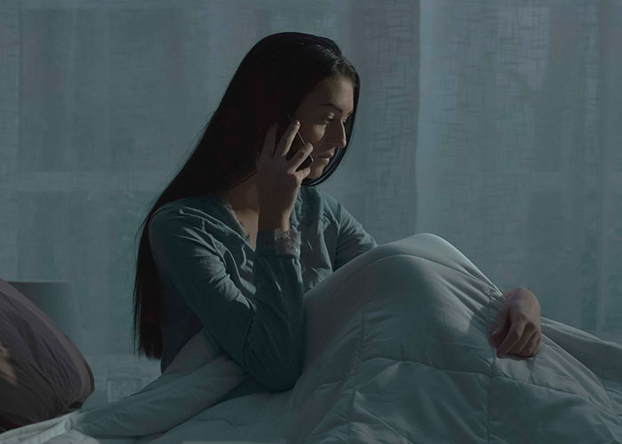 Woman on phone, sitting on bed at night, reflecting on her relationship after being ditched with a newborn by boyfriend. Woman on phone, sitting on bed at night, reflecting on her relationship after being ditched with a newborn by boyfriend.