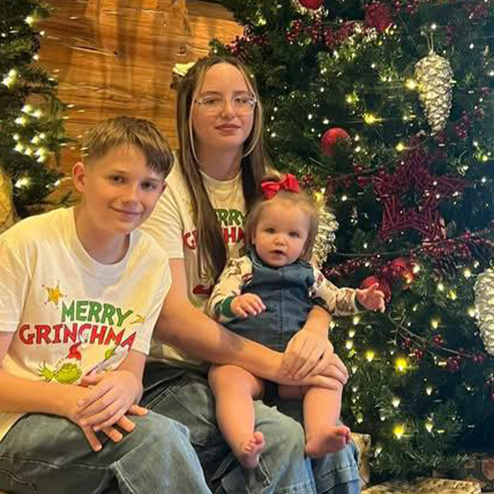 Three children sitting by a decorated Christmas tree during a family holiday gathering with a festive atmosphere. Three children sitting by a decorated Christmas tree during a family holiday gathering with a festive atmosphere.
