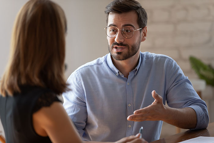 Man confidently mansplaining to a woman during a serious conversation in a cozy indoor setting.