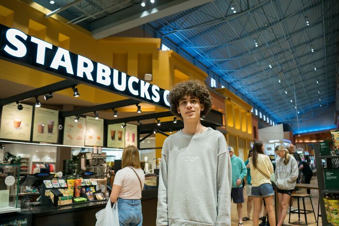 Young man standing in a busy Starbucks coffee shop illustrating examples of instant karma in everyday behavior.