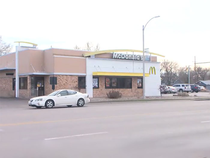 McDonald's drive-thru exterior with a white car passing by, scene related to a freak drive-thru accident incident.