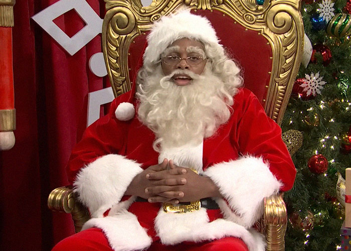 Person dressed as Santa Claus sitting on an ornate gold chair, sharing stories about famous people they’ve met.