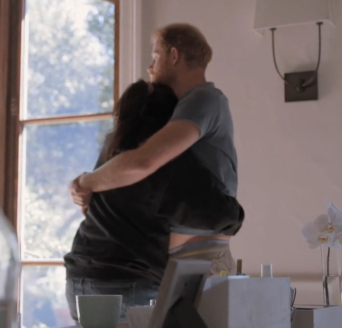 Couple embracing indoors near window with sunlight, illustrating PR gurus cutting ties with Prince Harry and Meghan Markle.