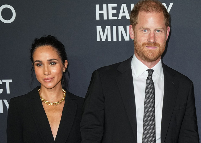 Meghan Markle and Prince Harry attending a formal event, dressed in black, with a dark backdrop featuring white text. Meghan Markle and Prince Harry attending a formal event, dressed in black, with a dark backdrop featuring white text.