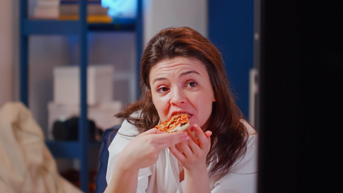 Woman eating pizza while watching something, illustrating men share lessons about women from marriage and relationships.