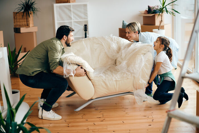 Family moving a couch together in their new home, illustrating men share things they learned about women from relationships.