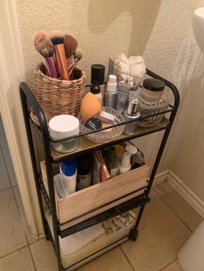 Makeup brushes, skincare products, and beauty essentials organized on a three-tier cart reflecting women’s relationship routines.