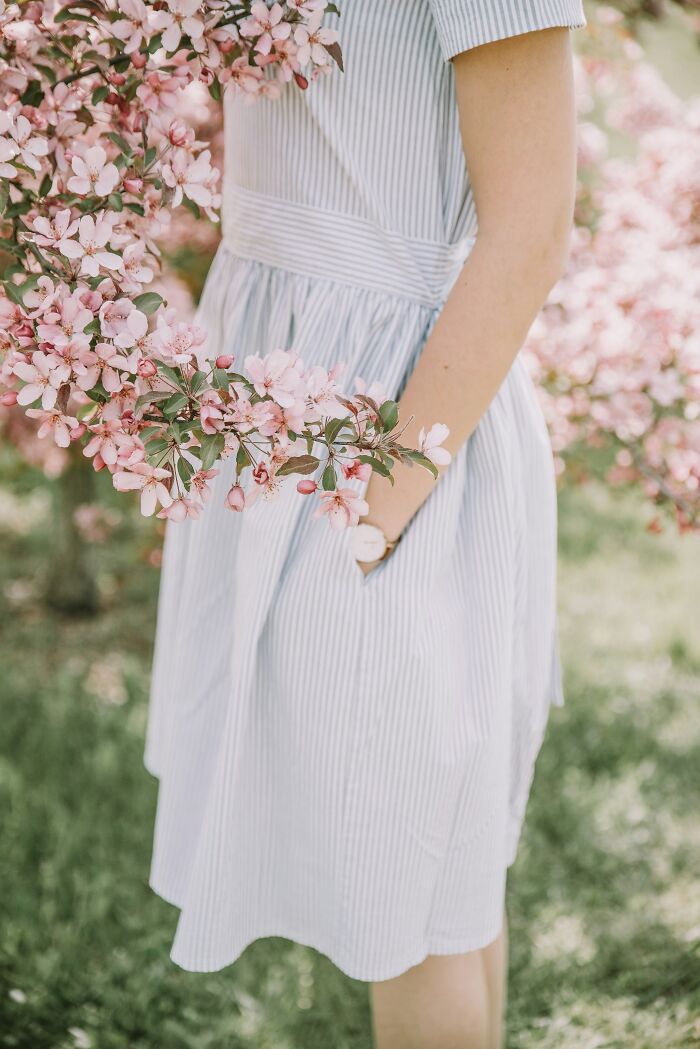 Woman in a striped dress standing near blooming pink flowers, illustrating insights from marriage and relationships about women.