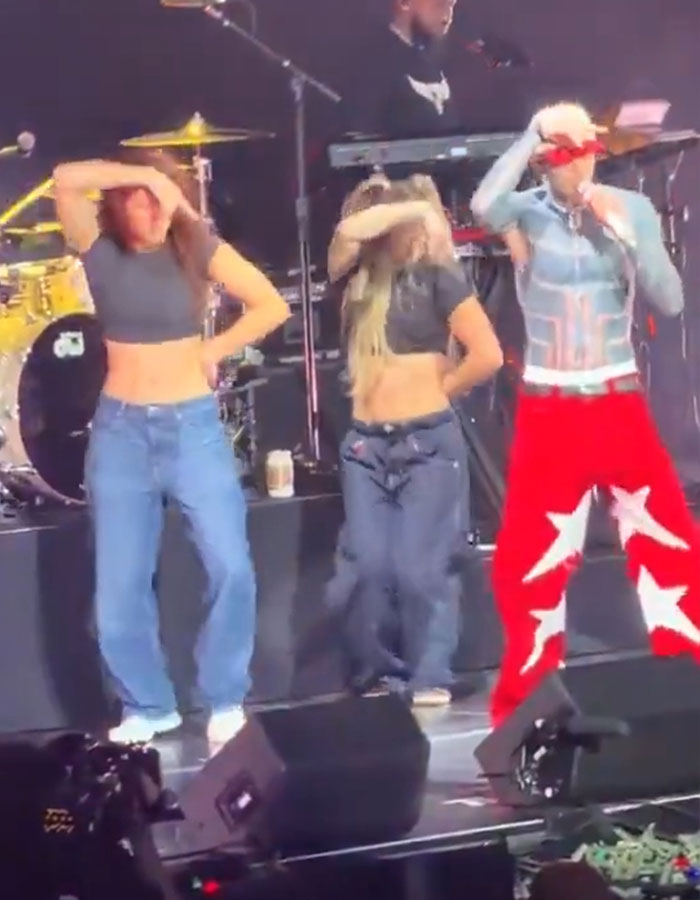 Machine Gun Kelly performing on stage with dancers in casual outfits during boy band dance routine.