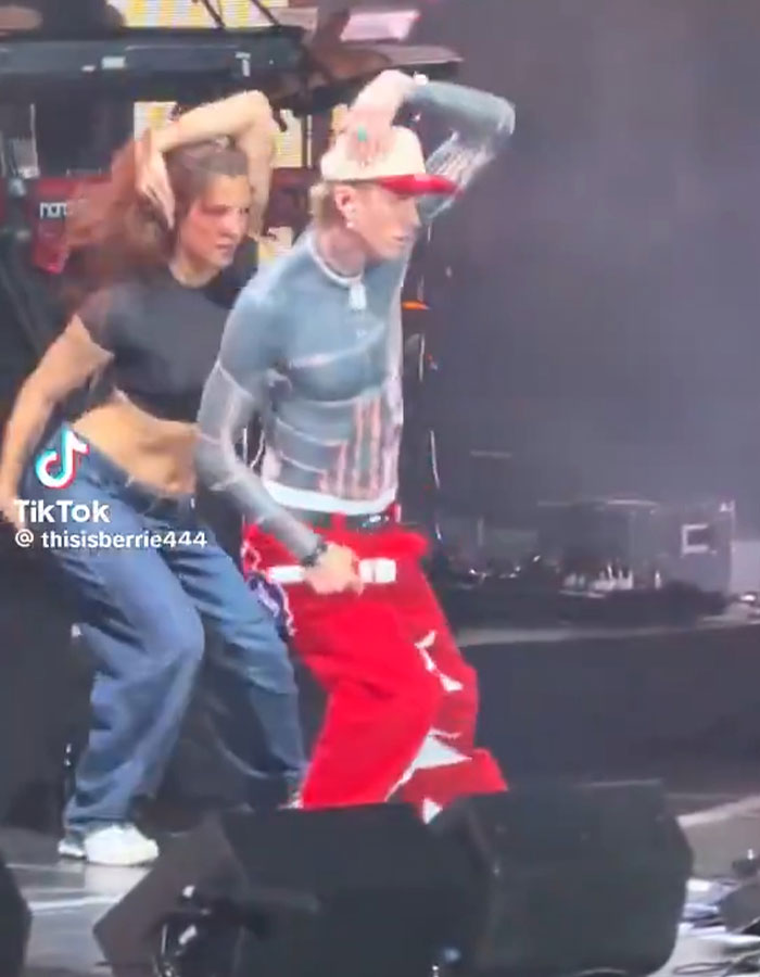 Machine Gun Kelly dancing on stage with a backup dancer in casual streetwear during a live performance.
