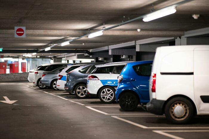 Cars parked in an underground garage showing a potential glitch in the system with parking space usage and sign placement.