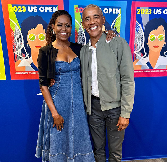 Michelle Obama and Barack Obama smiling together at the 2023 US Open event with colorful tennis posters in the background Michelle Obama and Barack Obama smiling together at the 2023 US Open event with colorful tennis posters in the background