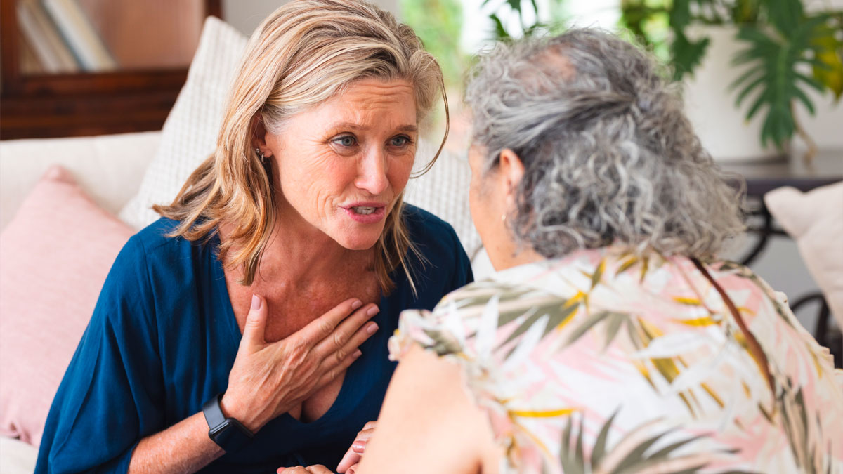 Middle-aged woman expressing concern to elder woman in a living room, depicting MIL and DIL family conflict after premature birth.