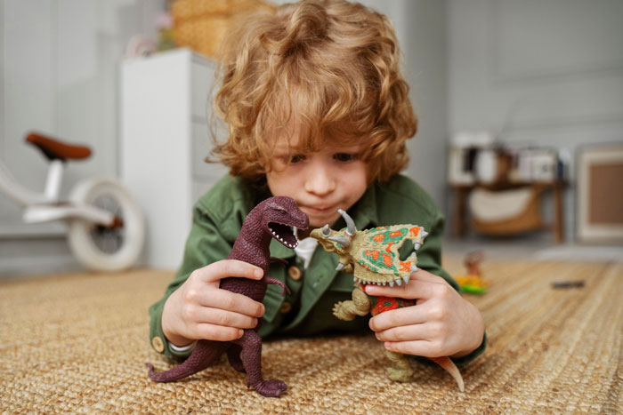 Young child playing on floor with dinosaur toys, capturing a playful moment related to grandma and Christmas gifts competition. Young child playing on floor with dinosaur toys, capturing a playful moment related to grandma and Christmas gifts competition.
