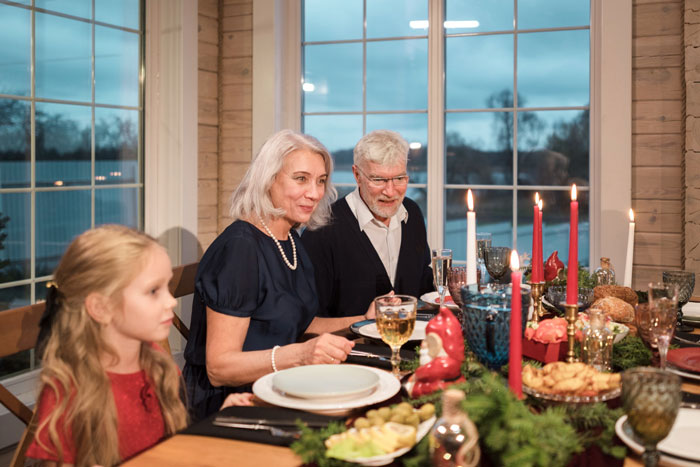 Family gathered around a mil house Christmas dinner table with festive decorations and a dog nearby. Family gathered around a mil house Christmas dinner table with festive decorations and a dog nearby.