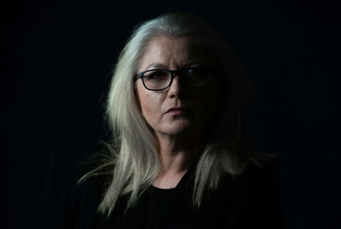 Middle-aged woman with glasses looking serious in dark lighting, depicting unhinged MIL losing job over promotion conflict. Middle-aged woman with glasses looking serious in dark lighting, depicting unhinged MIL losing job over promotion conflict.