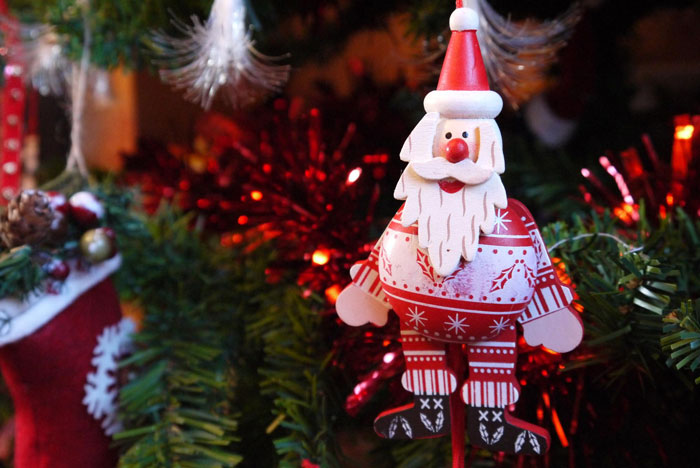 Wooden Santa Claus Christmas ornament hanging on a decorated tree, highlighting sentimental holiday decorations.