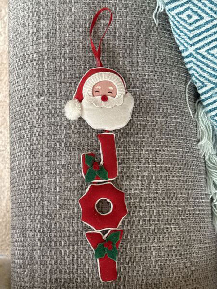 Felt Christmas ornament spelling JOY with Santa face and holly, representing sentimental Christmas ornaments.