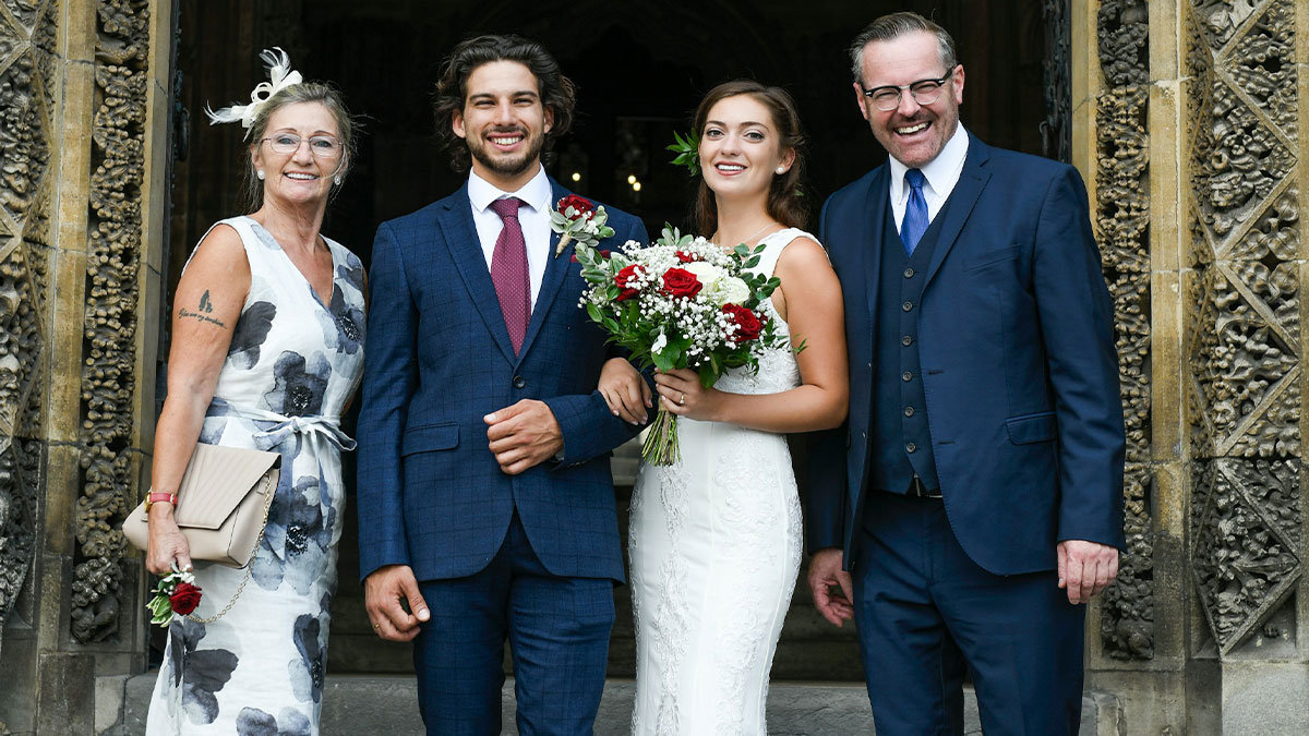 Bride and groom smiling with family outside ornate building, wedding illustration plan to make bride look ugly backfires