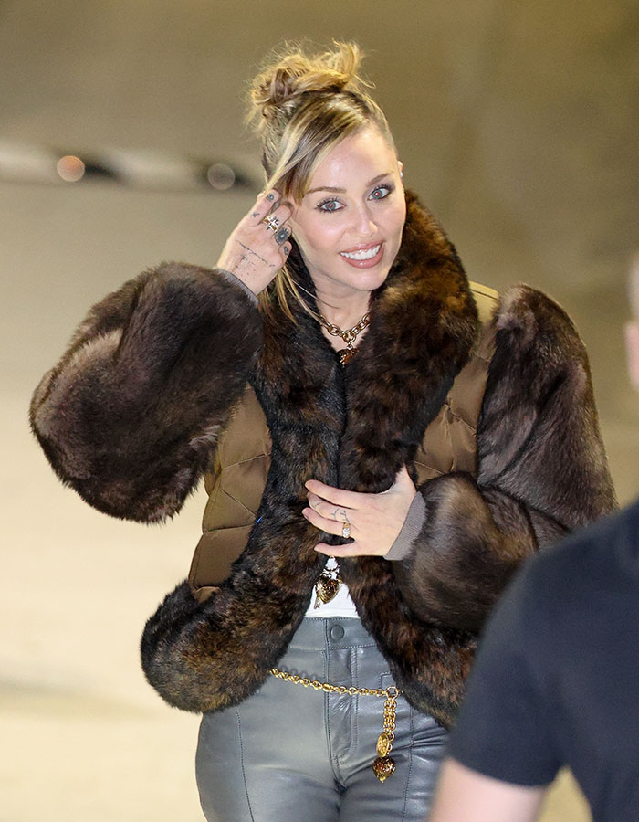Miley Cyrus smiling with youthful glow, wearing a fur jacket and stylish accessories during her viral makeover moment. Miley Cyrus smiling with youthful glow, wearing a fur jacket and stylish accessories during her viral makeover moment.