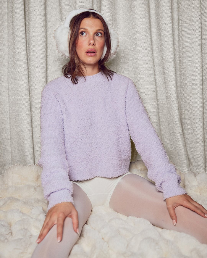 Young woman in lavender sweater and earmuffs sitting on faux fur with a snowy winter look sparking plastic surgery rumors. Young woman in lavender sweater and earmuffs sitting on faux fur with a snowy winter look sparking plastic surgery rumors.