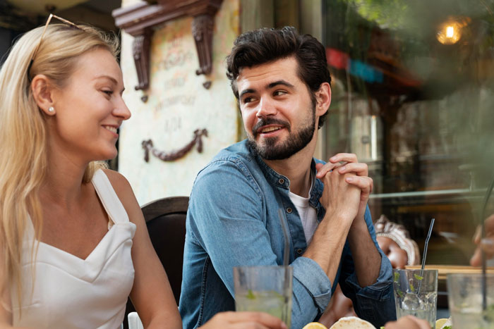 Young man and woman having a casual conversation at a restaurant, representing wedding family tensions and tantrums.