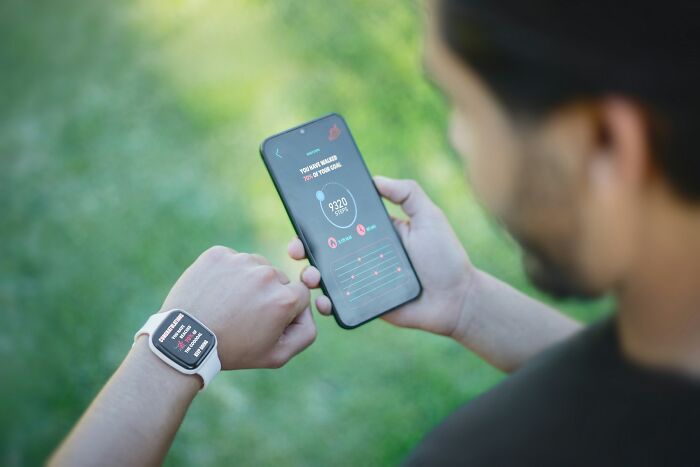 Person checking fitness tracker and smartphone app outdoors illustrating everyday things people accidentally did wrong.
