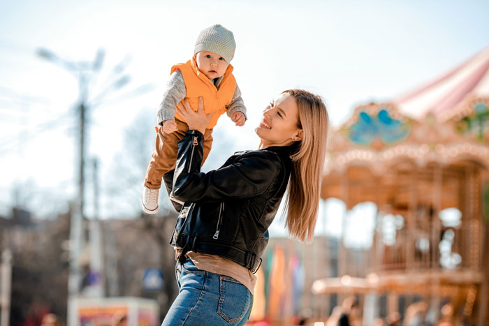 Mom holding baby at amusement park highlighting Disney dream with family and the cost of debt and guilt involved