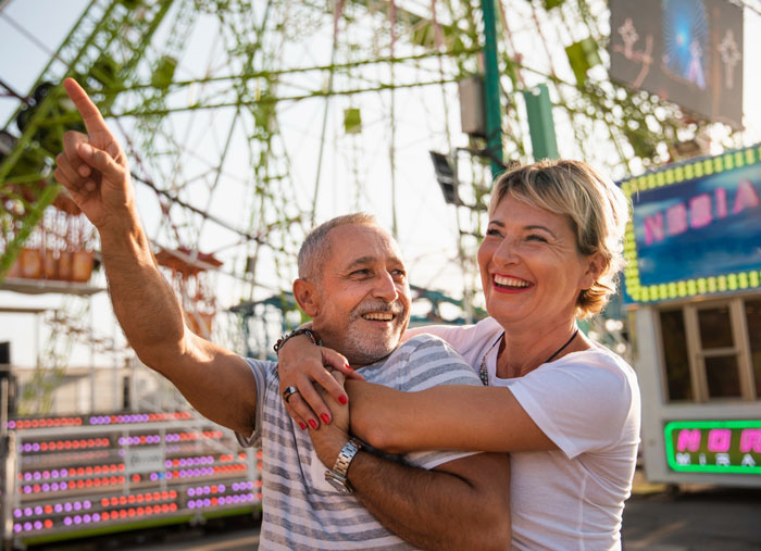 Smiling couple enjoying a theme park, highlighting the impact of a mom’s Disney dream causing family debt and guilt.