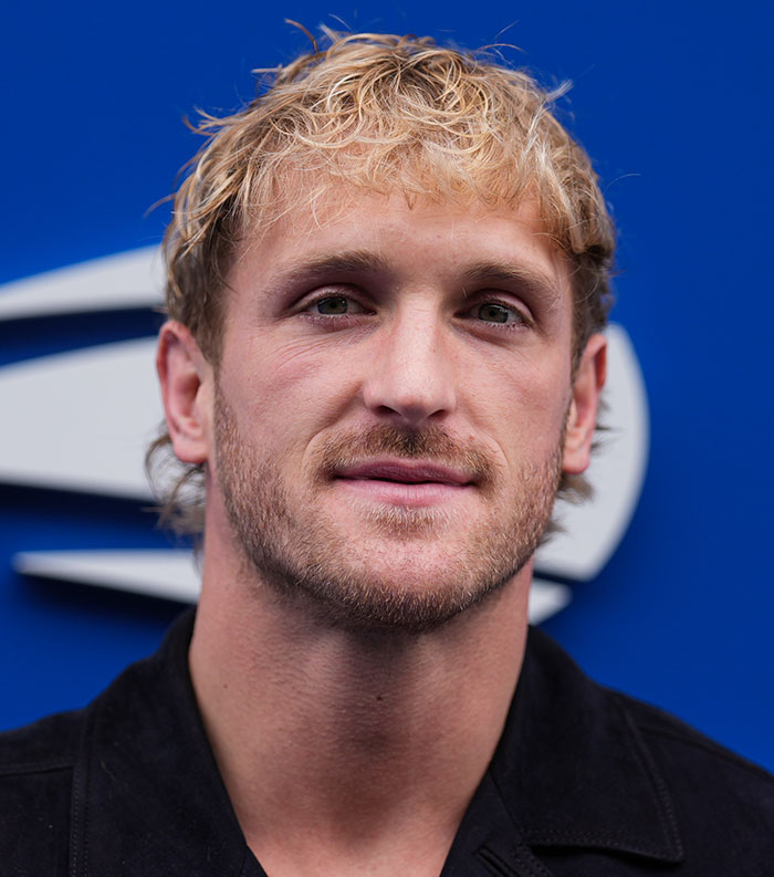 Close-up of a man with blond curly hair and beard, representing most disliked celebrities 2025 in a blue background.