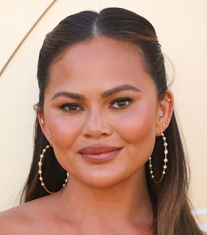 Close-up of a woman with hoop earrings and smooth hair, representing the most disliked celebrities of 2025.