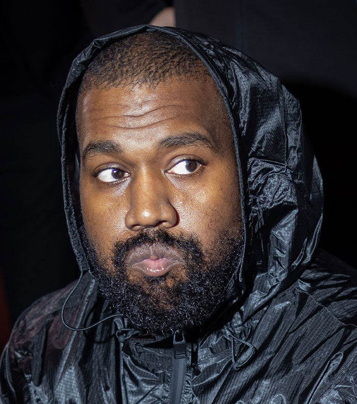 Close-up of a man in a black hooded jacket with a serious expression, representing most disliked celebrities of 2025.