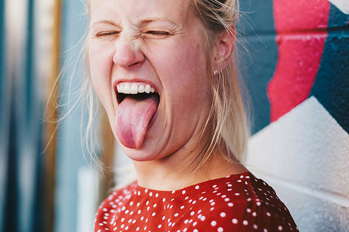 Woman in a red polka dot shirt making a funny face illustrating wildest examples of wrong self-diagnoses shared by doctors
