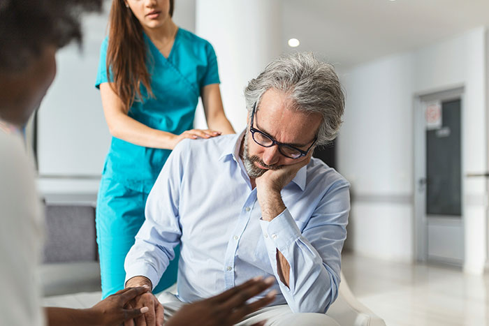 Doctor comforting a worried middle-aged man, illustrating examples of wrong self-diagnoses in a medical setting.