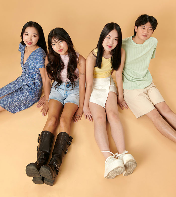 Four young people from different countries sitting together on a beige floor, representing diverse foreigners denying popular myths.