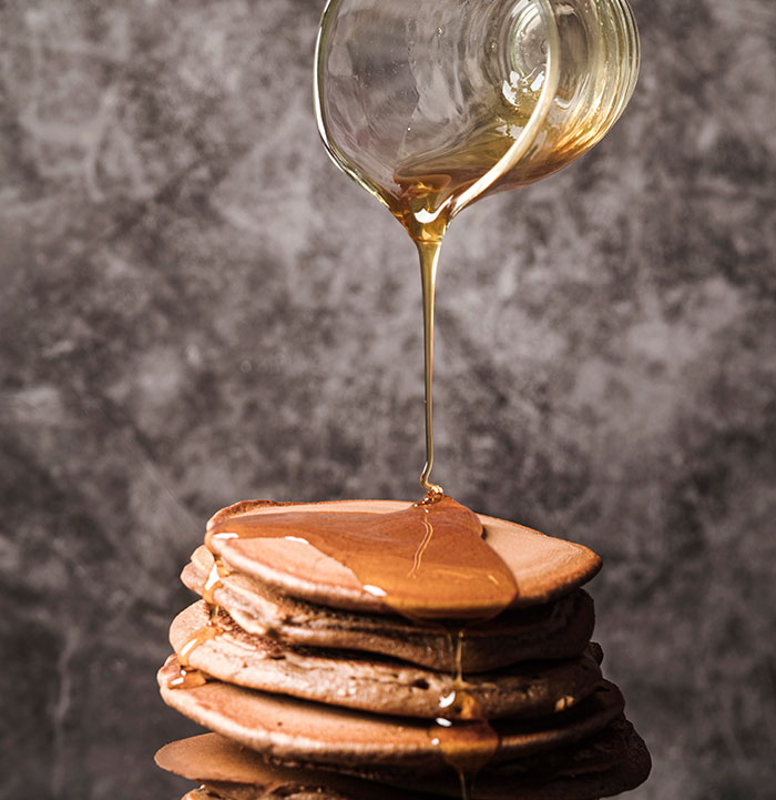 Stack of pancakes with syrup being poured, illustrating popular myths foreigners believe about food from different countries.