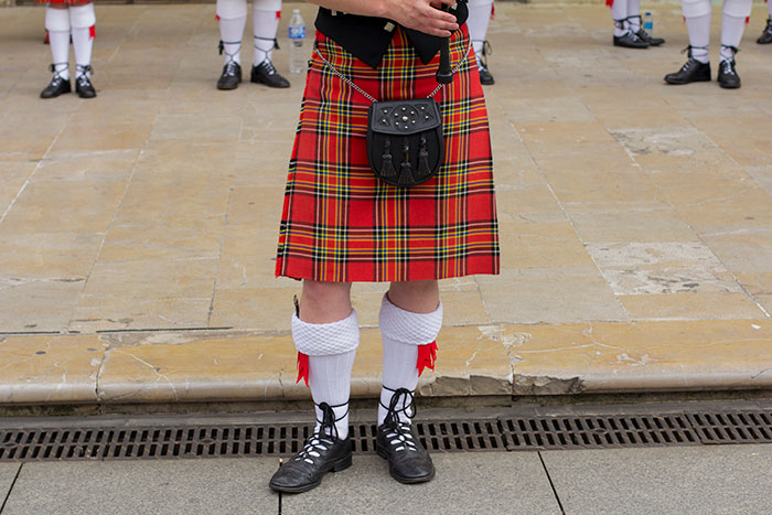 Man wearing traditional Scottish kilt and accessories, representing people from different countries denying popular myths.