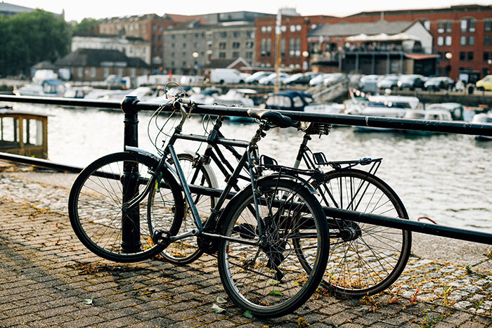 Bicycles locked along waterfront in a city harbor, illustrating people from different countries and cultural myths.