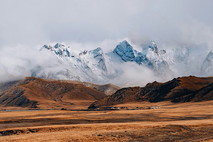 Mountain landscape with snowy peaks and a vast plain, illustrating people from different countries denying popular myths.