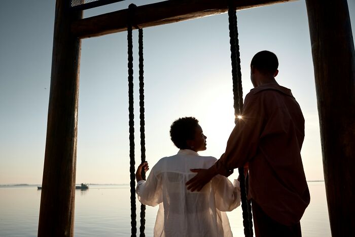 Couple standing by a lakeside swing at sunset, illustrating reflection on harmless but toxic habits discussion.