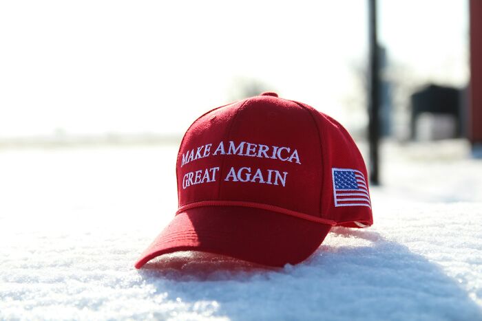 Red Make America Great Again hat resting on snow, symbolizing signs of someone stuck in their high school era years later.