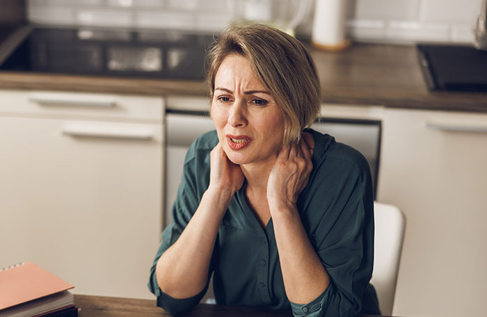Stressed woman sitting at kitchen table upset after learning daughter wants to honor dad's bestie as mom at wedding.