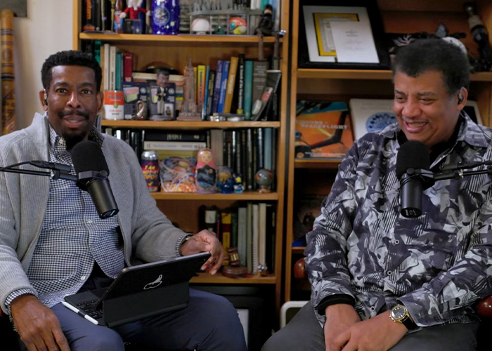 Two men in a casual podcast setup discussing Neil deGrasse Tyson&rsquo;s explanation of Rudolph&rsquo;s reindeer gender.