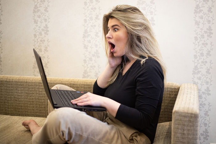 Woman on couch shocked by laptop screen, illustrating karma for entitled nephew using credit card for games